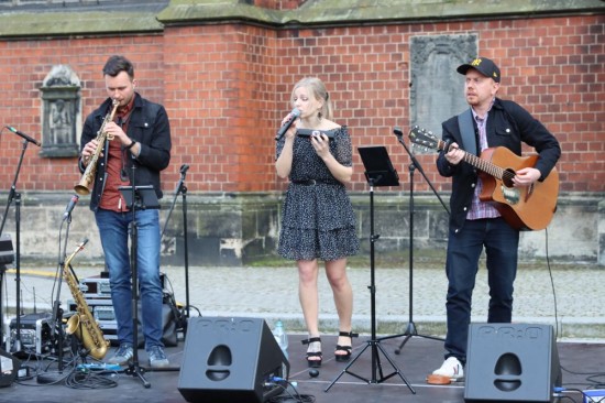 Muzyczne trio na scenie - wokalistka, gitarzysta i saksofonista